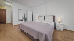 biała sypialnia z dużym łóżkiem i drewnianą podłogą w obiekcie Deluxe City AS Apartment - FREE PARKING w Zagrzebiu