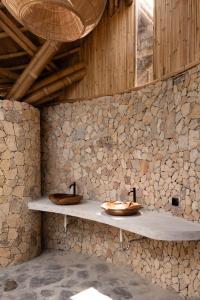 a bathroom with two sinks in a stone wall at Villa con Piscina Vista Mare - Lussuosa - Villa Chiara, Anima Eco Lodge in Selong Belanak