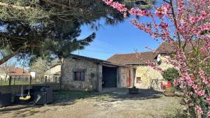 a stone house with a yard with pink flowers at Le gite de nathye in Saint-Junien