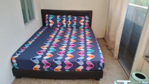 ein Bett mit farbenfroher Decke in einem Zimmer in der Unterkunft Property King in Singapur