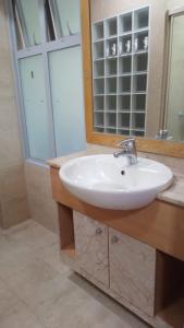 een badkamer met een witte wastafel en een spiegel bij Property King in Singapore