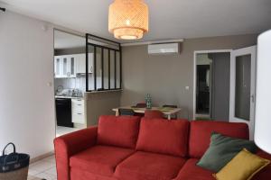 sala de estar con sofá rojo y cocina en Appartement lumineux terrasse piscine, en Cugnaux