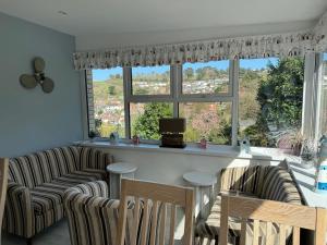 a living room with two chairs and a bar with a large window at Cairn House - Bed & Breakfast in Ilfracombe