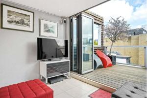 a living room with a television and a balcony at Multi-Award Winning 7 Storey Home - Near Shoreditch in London
