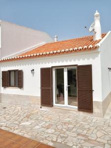 a white house with brown shutters on it at Casa Raios de Sol in Burgau
