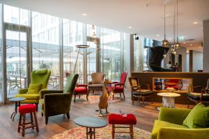 a lobby with colorful chairs and tables and windows at mightyTwice Hotel Achern in Achern