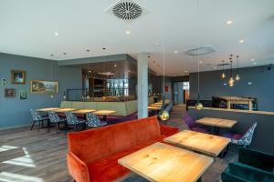 a lobby with a couch and tables and a bar at mightyTwice Hotel Achern in Achern