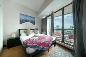 a bedroom with a bed and a large window at KL Tower Makati Apartments by PH Staycation in Manila