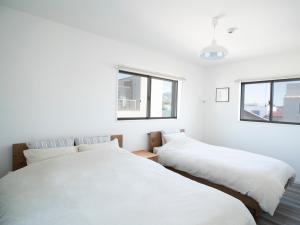 GLOCE長谷 QRPハウスKAMAKURA في كاماكورا: سريرين في غرفة بها نافذتين