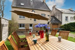 a wooden table with an umbrella and flowers on it at Maison 15pers 300m de la plage in Crozon