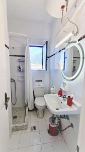 a white bathroom with a toilet and a sink at Gentle Breeze apartment in Kamena Vourla +37 photos