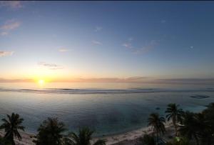 un tramonto su una spiaggia con palme e l'oceano di Beachfront Seaview Apartment a Città di Malé