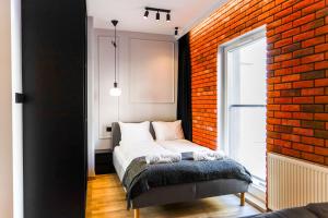 um quarto com uma cama e uma parede de tijolos em Red Old Town Apartament em Elblag