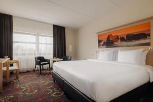 um quarto de hotel com uma cama grande e uma secretária em City Hotel Hengelo em Hengelo