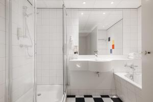 a white bathroom with a shower and a sink at City Hotel Hengelo in Hengelo