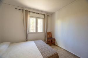 um quarto com uma cama, uma janela e uma cadeira em Villa Vilches em Els Poblets