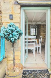 a porch with a table and a potted plant at Inglenook Cottage, The Cotswolds in Winchcombe