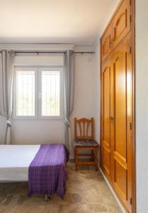 um quarto com uma cama, uma cadeira e uma janela em Villa Vilches em Els Poblets