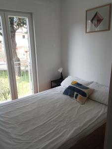 a bedroom with a white bed with a window at Green oasis Deda Božo in Rovinj