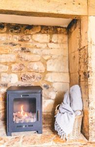 a fireplace in a room with a stone wall at Inglenook Cottage, The Cotswolds in Winchcombe