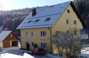 a yellow house with a snow covered roof at Haus Gisela in Forbach