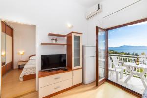 een woonkamer met een televisie en een balkon bij Apartments Palmero in Gradac