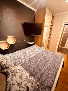 a bedroom with a bed and a flat screen tv at Komplett leilighet ved Tiller in Trondheim