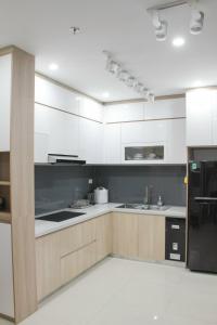 a kitchen with white cabinets and a black refrigerator at Ly Homestay - Nera Garden Huế in Hue