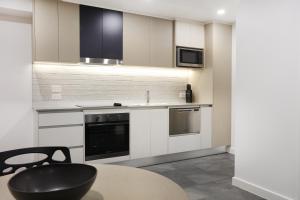 a kitchen with white cabinets and a table with a black chair at Southport Motel & Apartments in Gold Coast