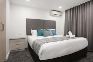 a bedroom with a large bed with blue pillows at Southport Motel & Apartments in Gold Coast