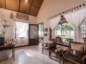a living room with chairs and a table and windows at Ho Tram Beach Boutique Resort & Spa in Ho Tram