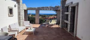 un patio con sillas blancas y vistas al océano en villa 32, en Castiadas