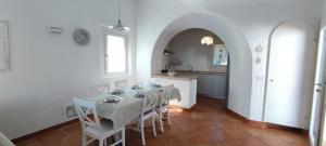 comedor blanco con mesa y cocina en villa 32, en Castiadas