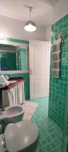 y baño con aseo, lavabo y azulejos verdes. en villa 32, en Castiadas 28 fotos más