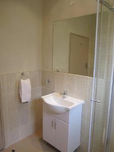 ein Bad mit einem Waschbecken und einem Spiegel in der Unterkunft Victoria Apartments in Livingstone