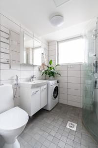 a white bathroom with a washing machine in it at Kodikas kahden makuuhuoneen asunto Tikkurilassa in Vantaa