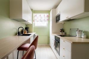 a kitchen with green walls and white cabinets and a counter at Kodikas kahden makuuhuoneen asunto Tikkurilassa in Vantaa