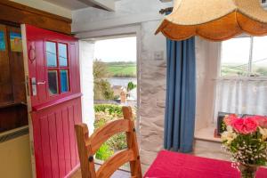 a dining room with a red door and a window at Maes yr Afon St Dogmaels in Saint Dogmaels