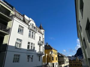 a white building with a yellow building next to it at Stylish big Jugend art nouveau apartment with balcony heart of Alesund in Ålesund