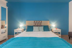 een blauwe kamer met een groot bed met 2 nachtkastjes bij Palazzo Spada - Appartamento Cigno con 2 camere da letto in Codigoro