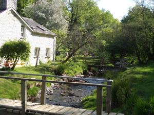 a bridge over a stream in front of a house at The Old Mill Devils Bridge in Llanilar