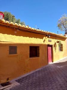 un edificio amarillo con puerta roja y entrada de ladrillo en La casita del Horno, en Pedralba
