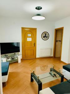 sala de estar con mesa de centro de cristal y TV en APARTAMENTOS TURISTICOS MONTASOL, en Montánchez