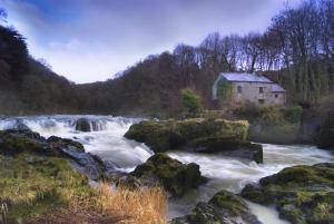 ein altes Haus am Ufer eines Flusses in der Unterkunft Blaenfforest Rose Cottage Newcastle Emlyn in Capel-Ifan