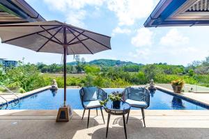 2 sillas y sombrilla junto a la piscina en Casa Asiatique — 5BR Villa in Laguna & Layan Beach, en Phuket