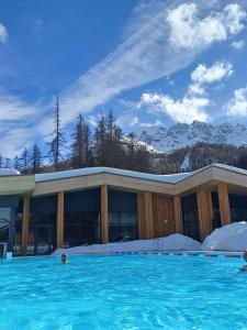 - une piscine en face d'un bâtiment avec des montagnes enneigées dans l'établissement Le grand cerf le Pelvou, à Vars