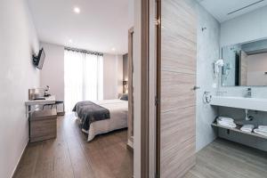 a bedroom with a bed and a bathroom with a sink at Hostal Boutique Aurora in Nerja