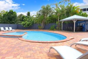 a swimming pool with two chairs and a gazebo at Southport Motel & Apartments in Gold Coast