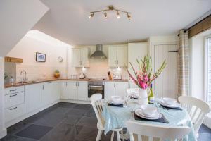 a kitchen with a table and white cabinets at Y Cartws Eglwyswrw in Eglwyswrw