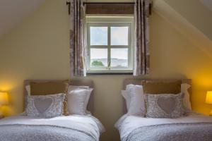 two beds in a bedroom with a window at Y Cartws Eglwyswrw in Eglwyswrw